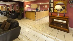 A hotel lobby with a reception desk, seating area, and a large mirror. - Pery's Hotel (Limerick)