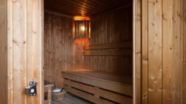 A sauna with wooden benches and a wall-mounted light fixture. - Pery's Hotel (Limerick)
