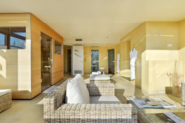 Un moderno espacio de spa con mobiliario de mimbre, una mesa de cristal y toallas en una pared.