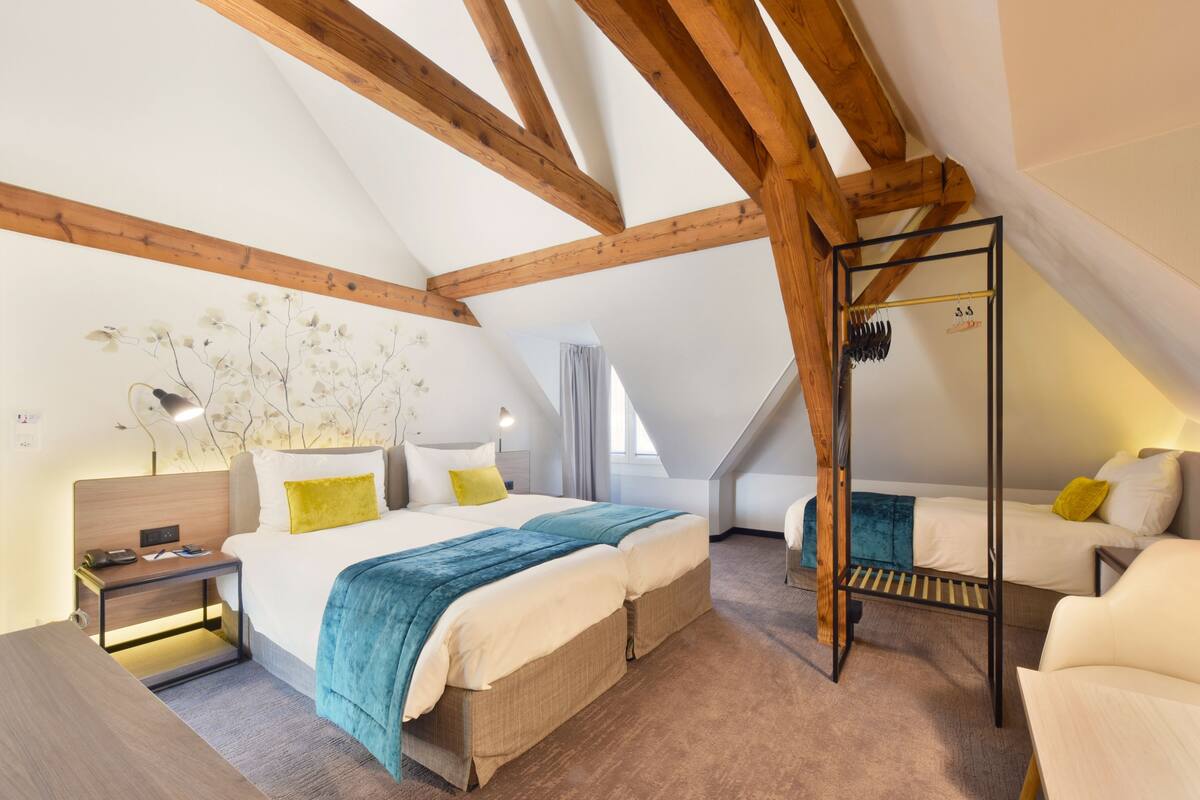 Ein Schlafzimmer mit Schlafgalerie, einem Bett mit blauer und weißer Bettdecke, einem Nachttisch, einem Hängesessel und einem kleinen Schreibtisch.