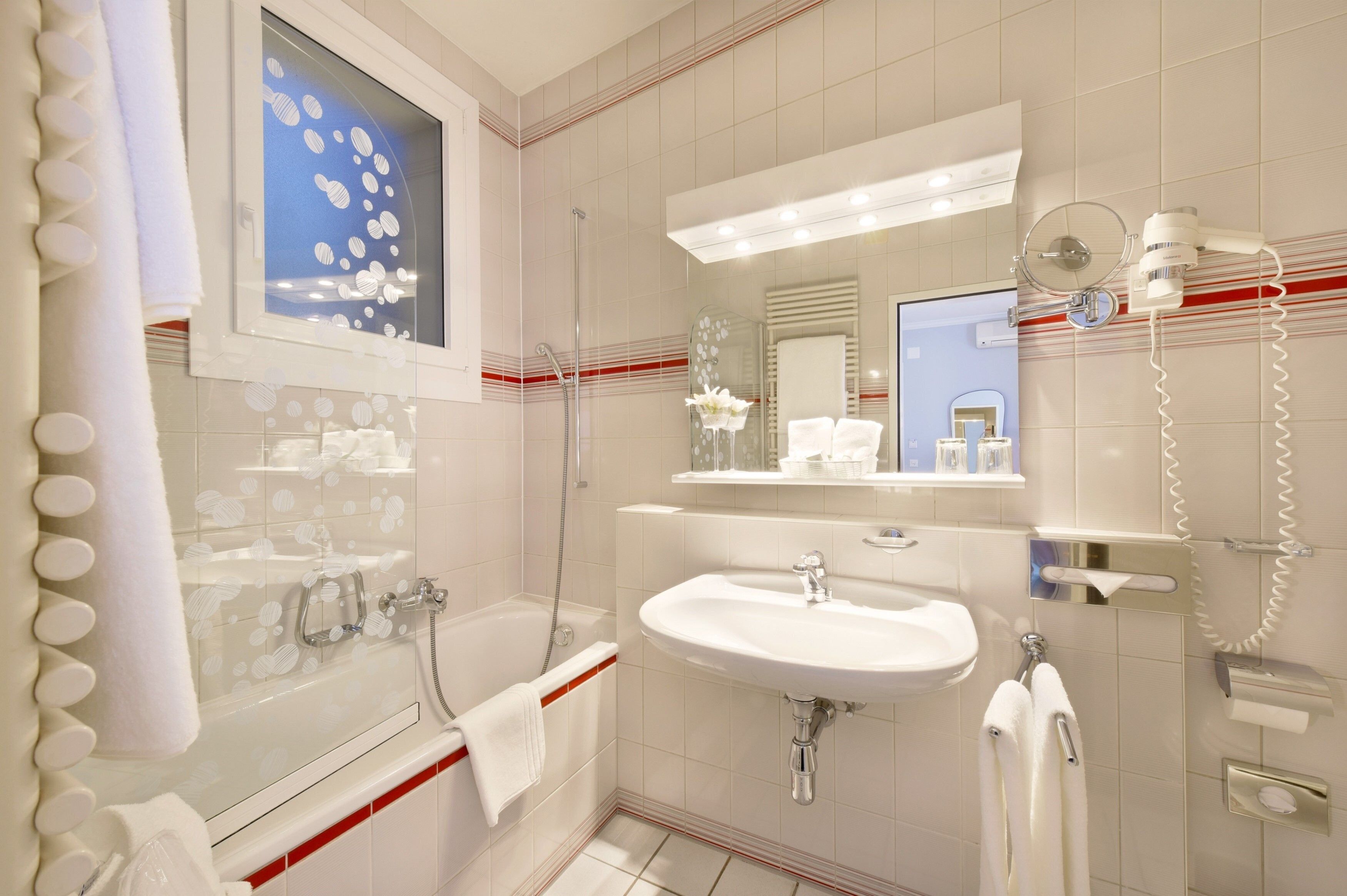 A modern bathroom with a glass-enclosed shower, a white sink, and a large mirror.