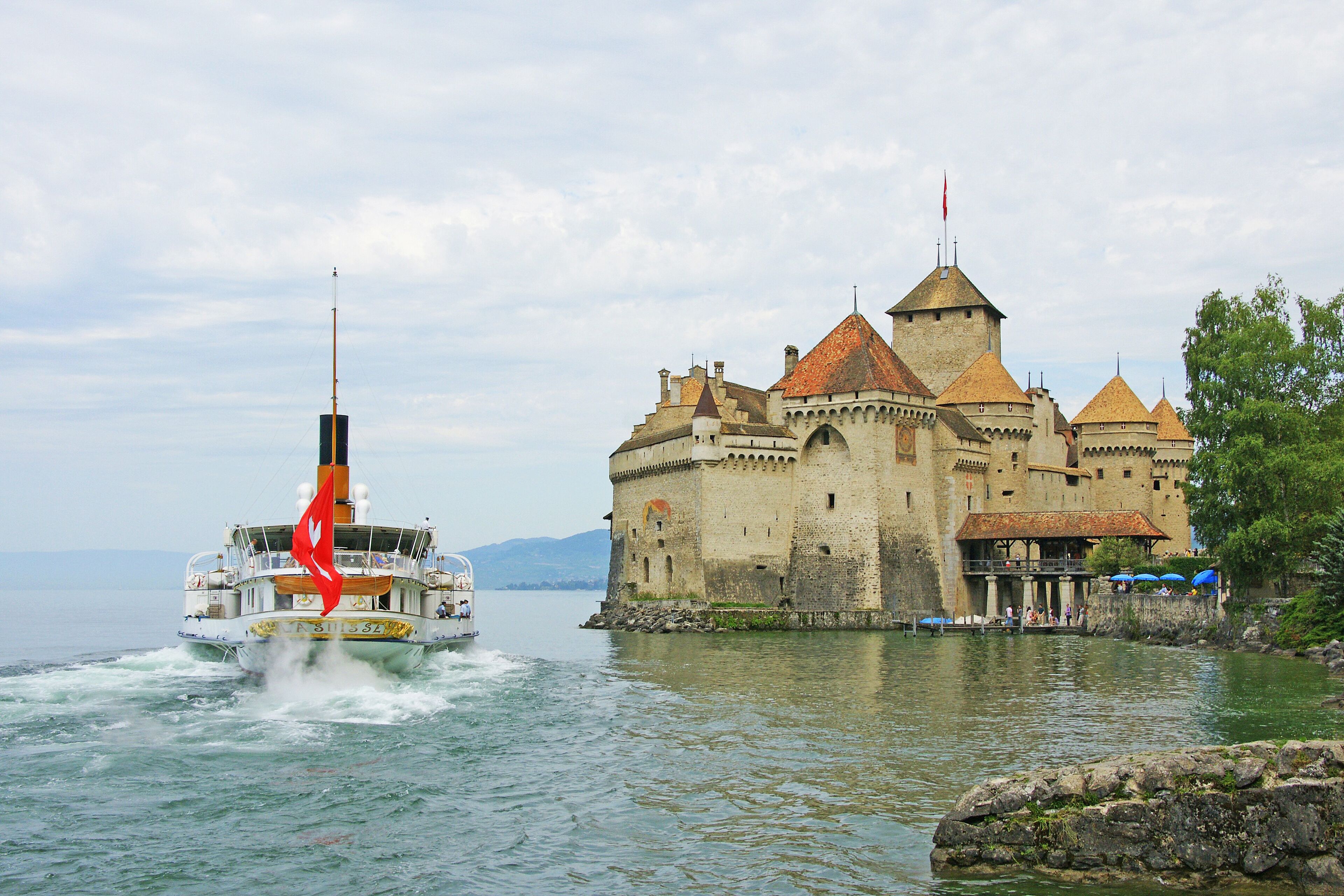 A castle by a lake with a boat in the foreground.