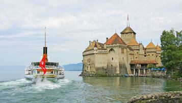 A castle by a lake with a boat in the foreground.