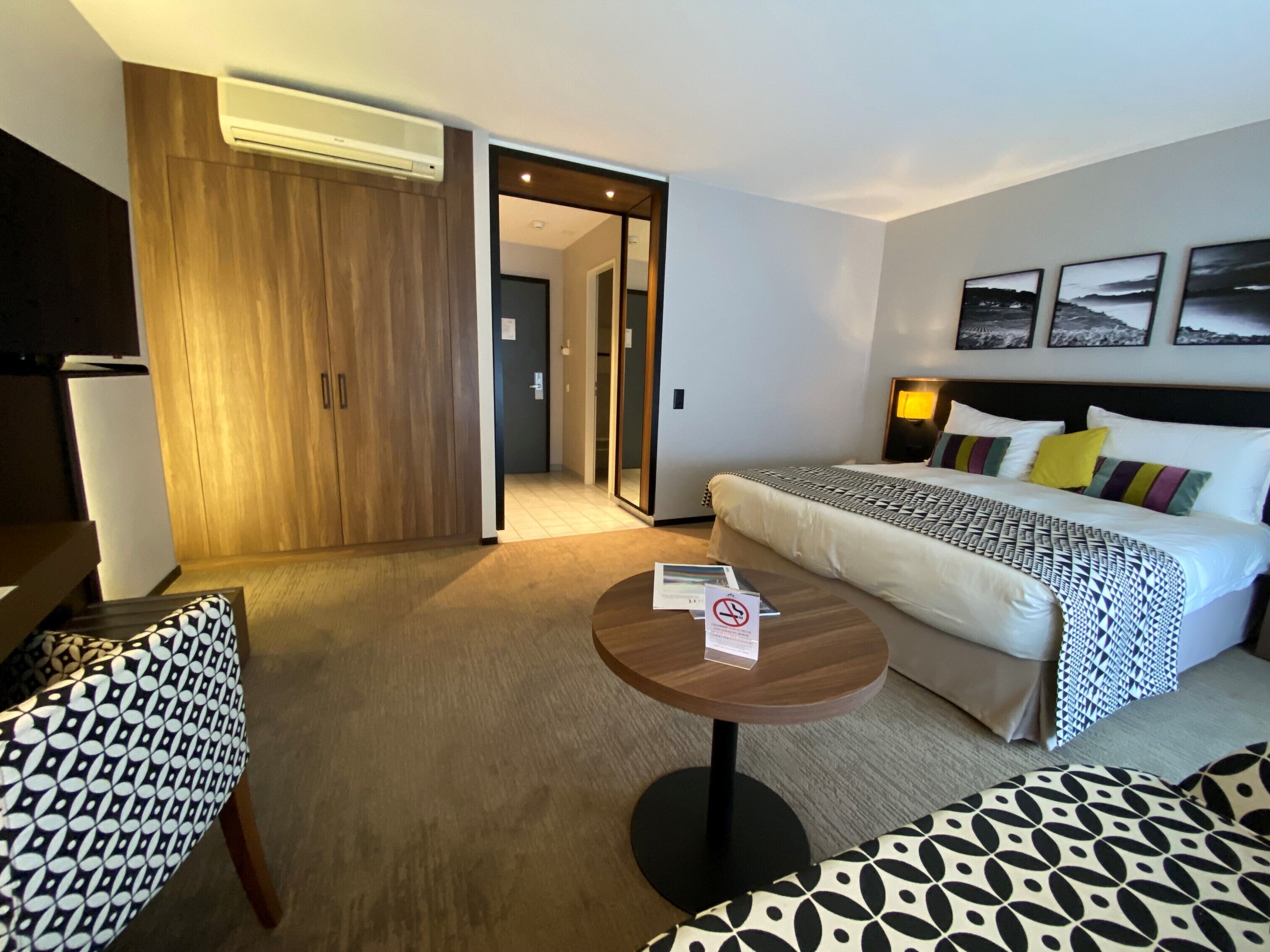 A hotel room with a bed, a small table, a sofa, and a wardrobe.