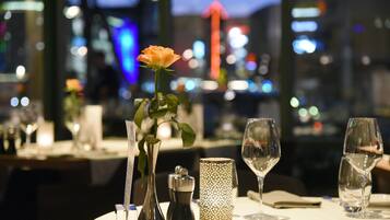 Ein gedeckter Restauranttisch mit Blumen, Salz- und Pfefferset, einer Kerze und Weingläsern.