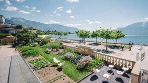 A terrace with a view of a lake and mountains, outdoor seating, and a garden area. - Astra Hotel Vevey (Vevey)