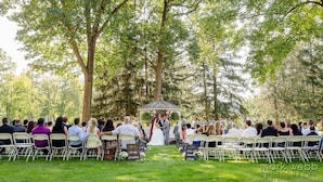 A wedding ceremony outdoors with guests seated on chairs facing a gazebo. - Lakeview Golf Resort (Morgantown)