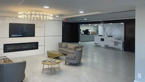 A modern interior with a seating area, a TV, a kitchen, and a reception desk. - Lakeview Golf Resort (Morgantown)
