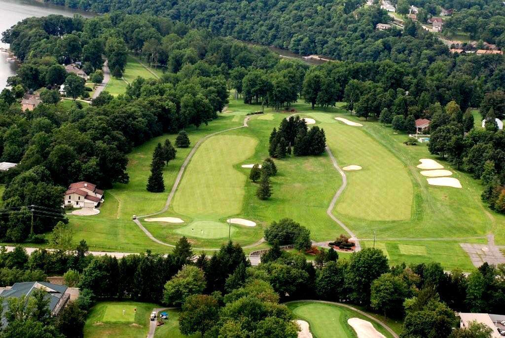 Vista aérea de um campo de golfe com vários greens, armadilhas de areia e um clube.