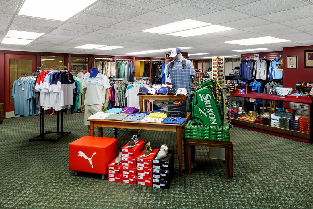 A retail store with clothing racks, a display table with hats and shoes, and a mannequin.
