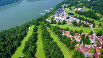 An aerial view of a lakeside property with a golf course, residential areas, and a large building complex.