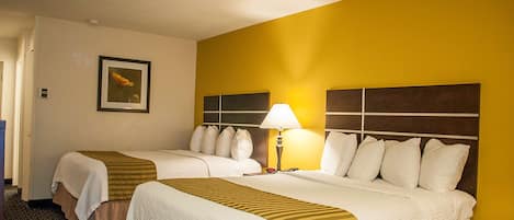 Una habitación de hotel con dos camas, una mesita de noche, una lámpara y un cuadro en la pared.