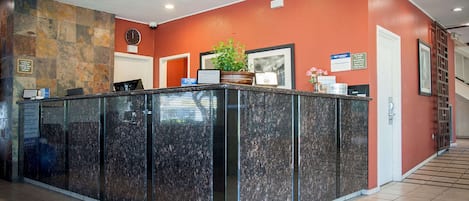 A reception desk with a stone wall, a potted plant, and framed pictures on the wall.