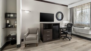 A modern hotel room with a desk, chair, television, and air conditioning unit. - Best Western Asheville Blue Ridge Parkway (Asheville)