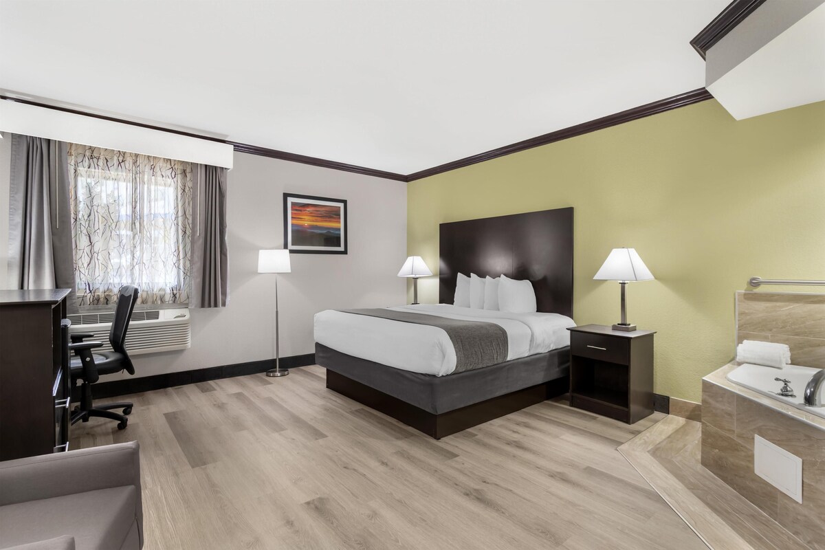 Une chambre d’hôtel avec un lit, des tables de chevet, un bureau et une chaise.