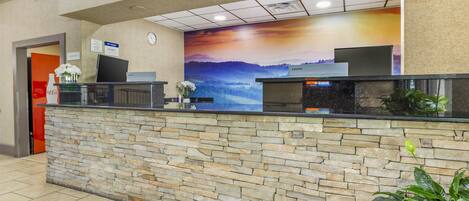 A reception desk with a stone facade, a clock, and a Lenovo computer.