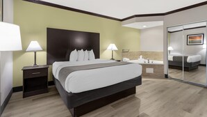 Une chambre d’hôtel avec un grand lit, des lampes de chevet, une table de chevet, une salle de bain avec un miroir et un tableau au mur.