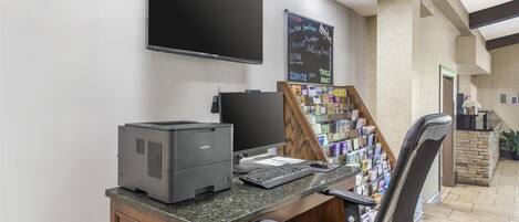 Un mostrador de recepción con una impresora Brother, un monitor de pantalla plana y un televisor montado en la pared.