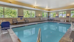 A swimming pool with clear blue water, surrounded by beige walls and large windows. - Best Western Asheville Blue Ridge Parkway (Asheville)