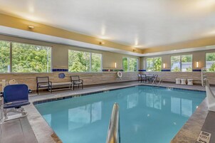A swimming pool with clear blue water, surrounded by beige walls and large windows.