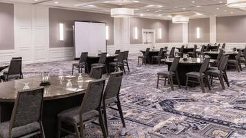 A conference room with multiple tables and chairs, a whiteboard, and a projector screen.