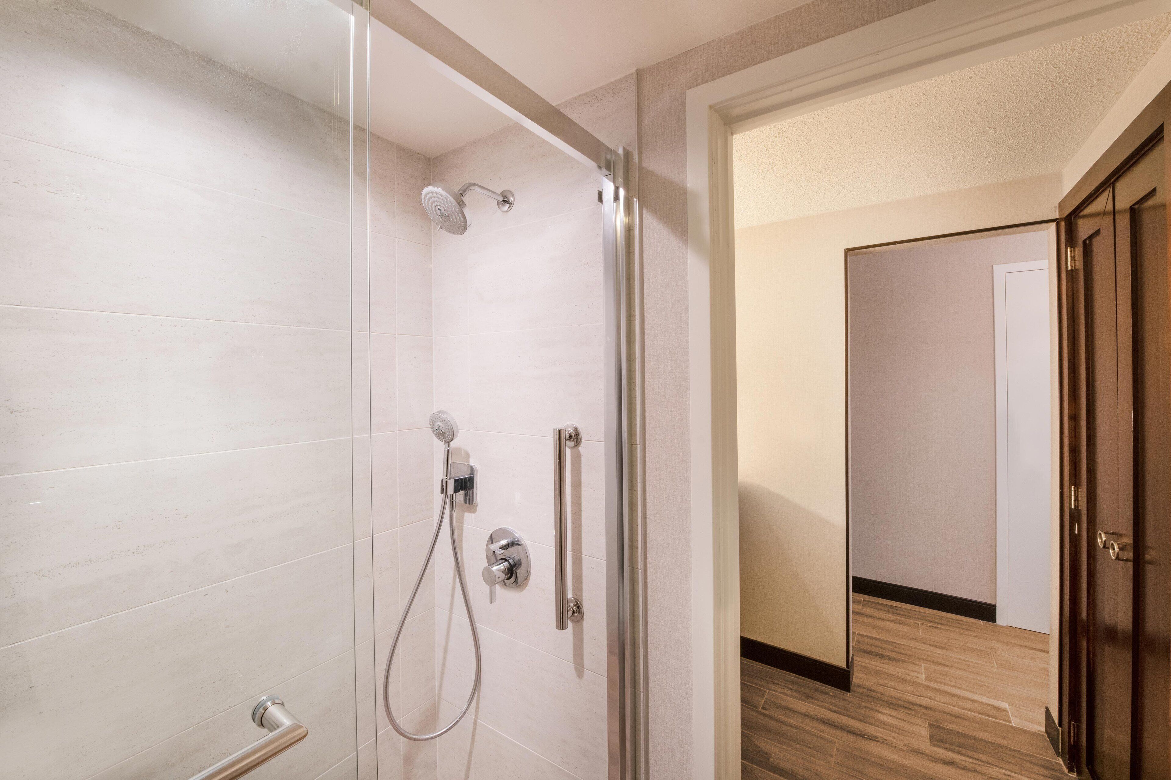 Ein modernes Badezimmer mit Duschkabine aus Glas, einer Handbrause und einem wandmontierten Wasserhahn.