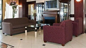 A living room with a sofa, armchairs, a coffee table, a fireplace, and a television. - Clarion Inn Fredericksburg North (Fredericksburg)