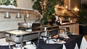 A buffet setup with multiple serving stations, including bowls and plates, and a variety of utensils. - Clarion Inn Fredericksburg North (Fredericksburg)