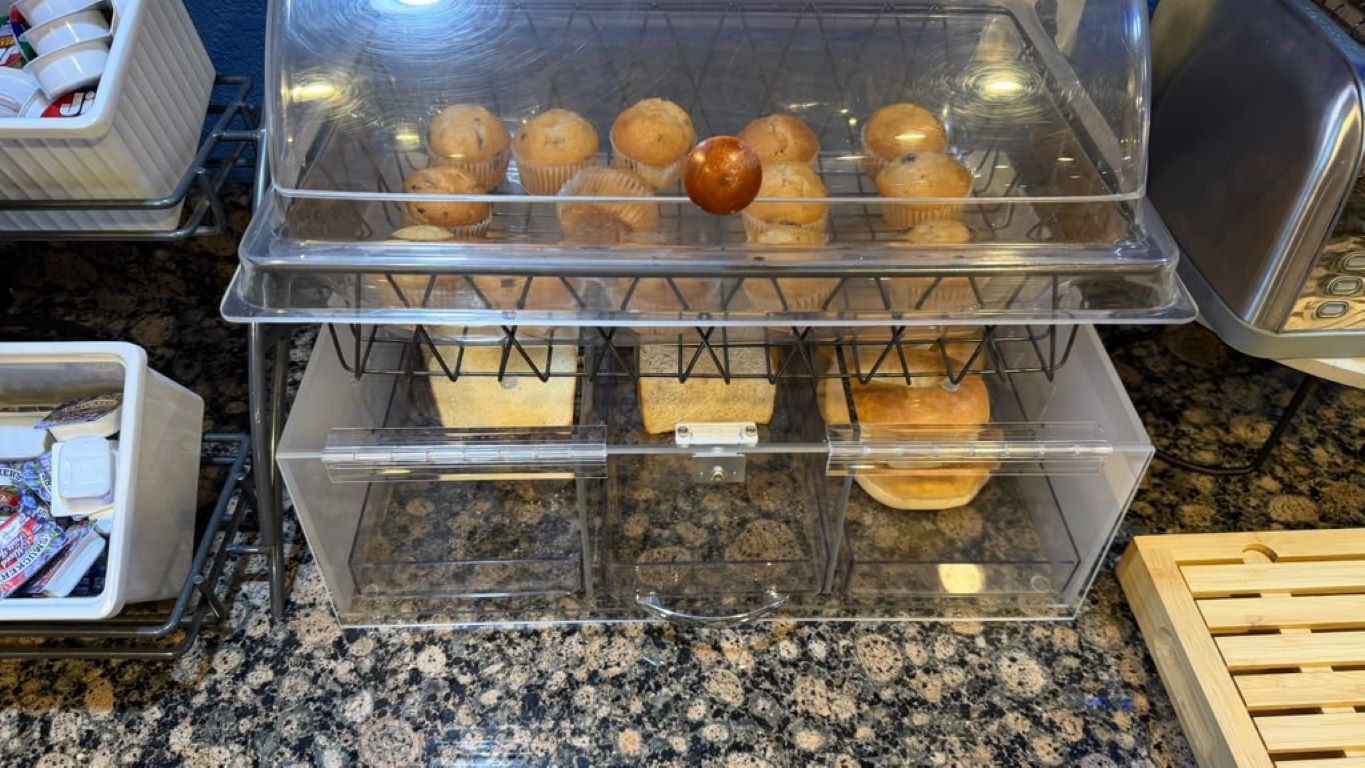 A bakery display with muffins and bread on shelves.