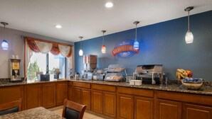 Una barra de desayuno con un letrero que dice 'Breakfast Corner', una máquina de café y diversas opciones para el desayuno.