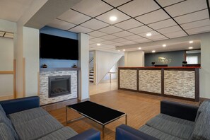 A hotel lobby with a fireplace, seating area, and a reception desk. - Baymont by Wyndham Waukesha (Waukesha)