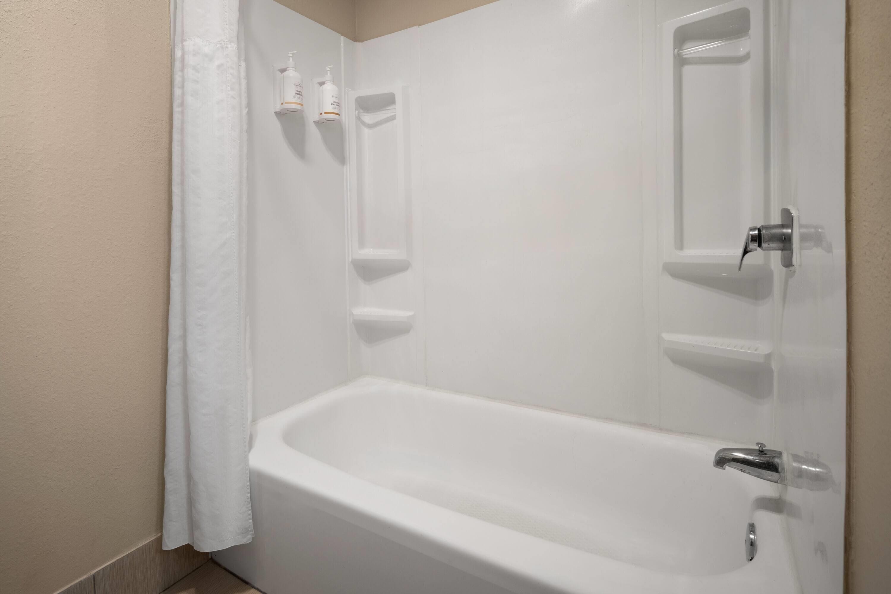 A white bathtub with a shower curtain, a towel rack, and a soap dispenser.