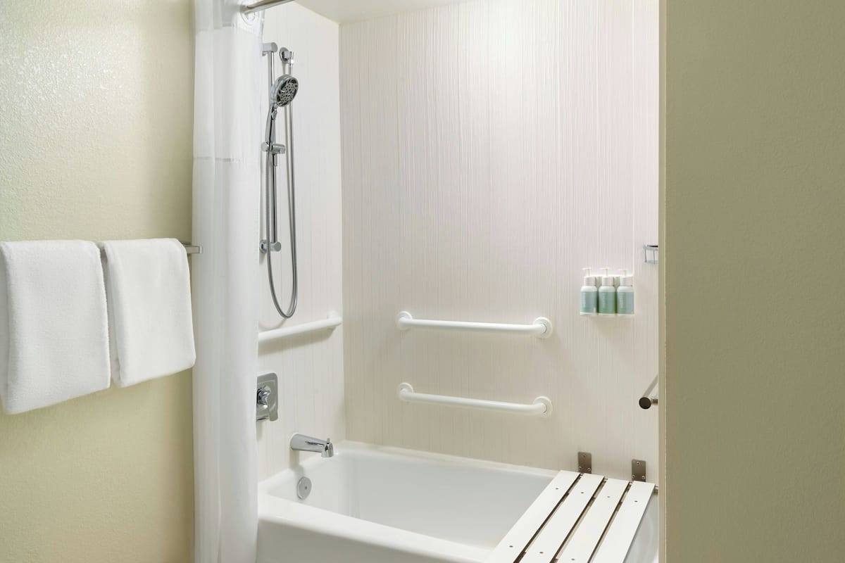 A bathroom with a bathtub, a shower, and a towel rack.