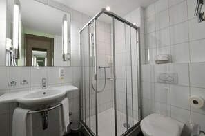 A modern bathroom with a glass-enclosed shower, a sink with a towel rack, and a toilet.
