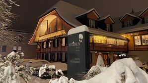 Un albergo con un cartello che recita "STERNEN MURI HOTEL RESTAURANT" e un paesaggio circostante innevato.