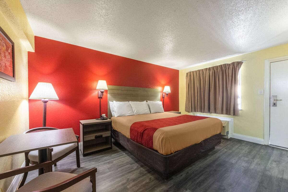 Una habitación de hotel con cama, mesitas de noche, escritorio y silla.