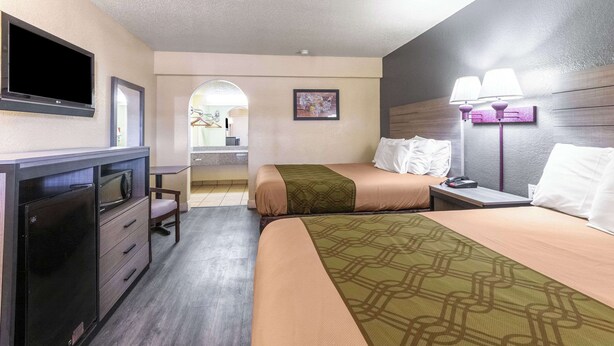 A hotel room with a bed, a desk, a TV, a lamp, and a bathroom visible through an archway. - Econo Lodge San Marcos University Area (San Marcos)