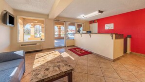 A hotel lobby with a reception desk, a sofa, a coffee table, and a large window providing a view of the outside. - Econo Lodge San Marcos University Area (San Marcos)