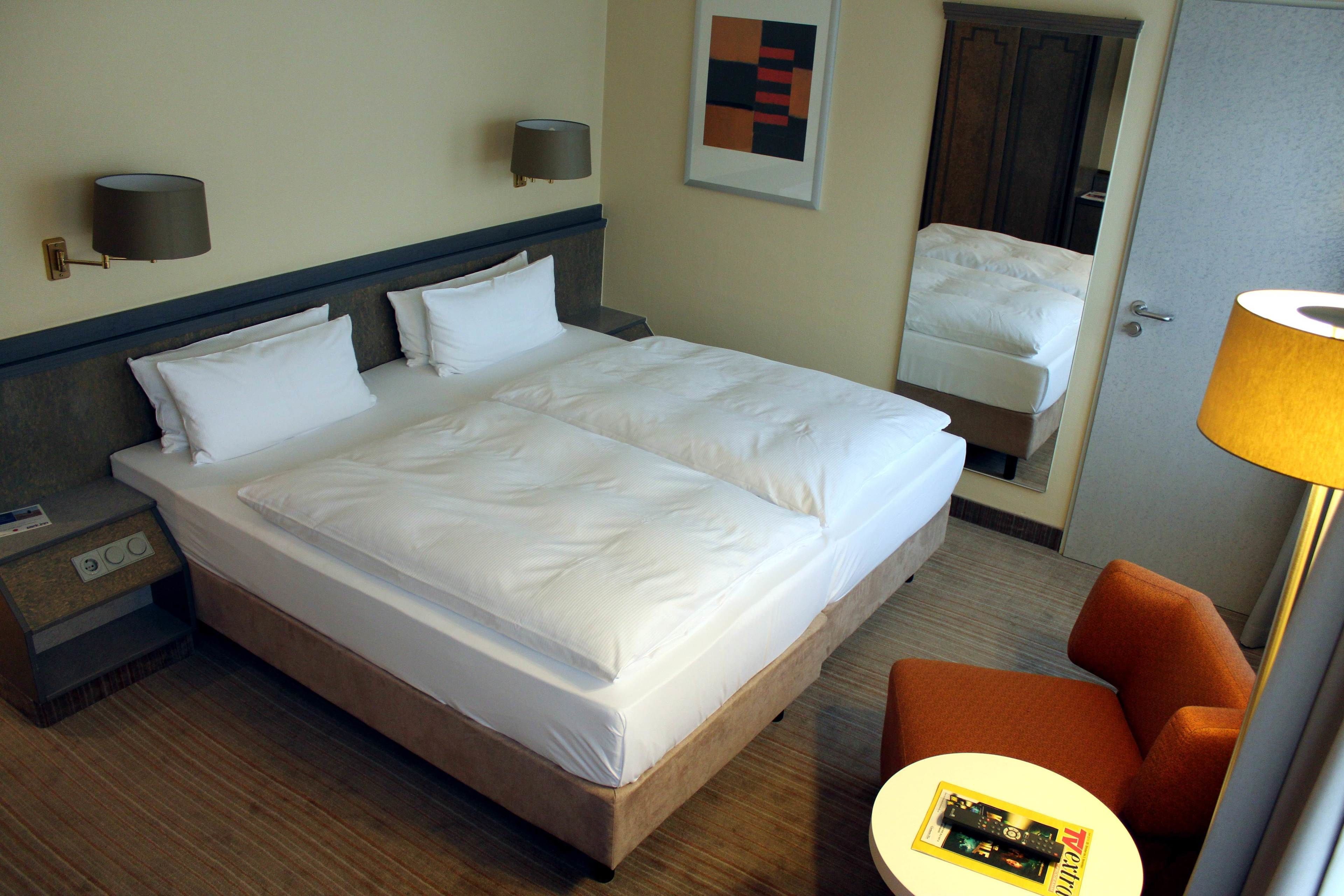 Een hotelkamer met een groot bed, een nachtkastje, een lamp en een stoel.