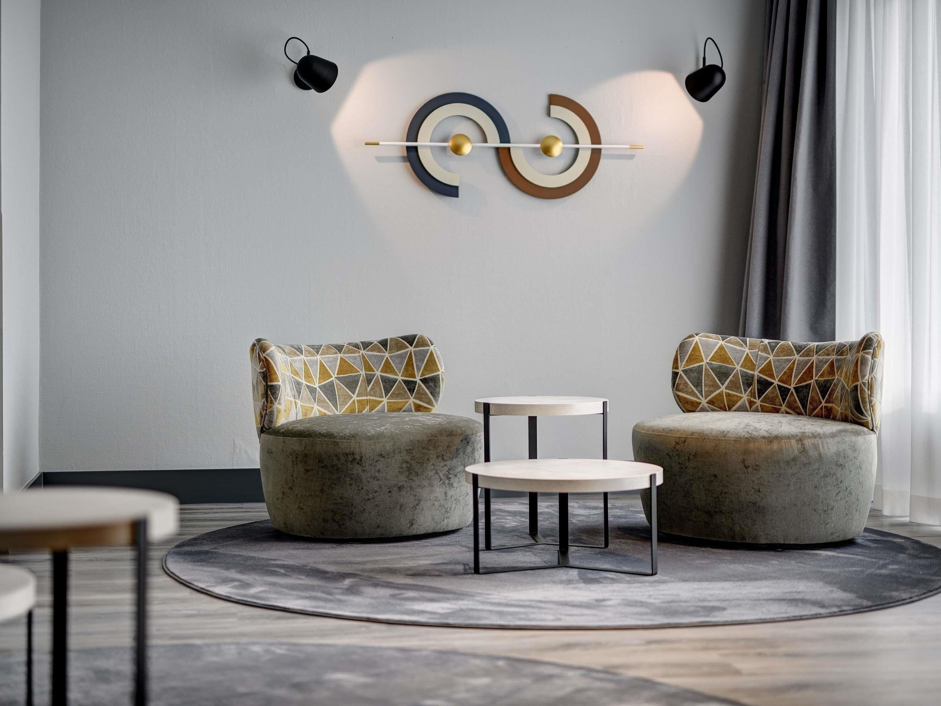 Un salon moderne avec deux canapés, une petite table ronde et un élément décoratif fixé au mur.
