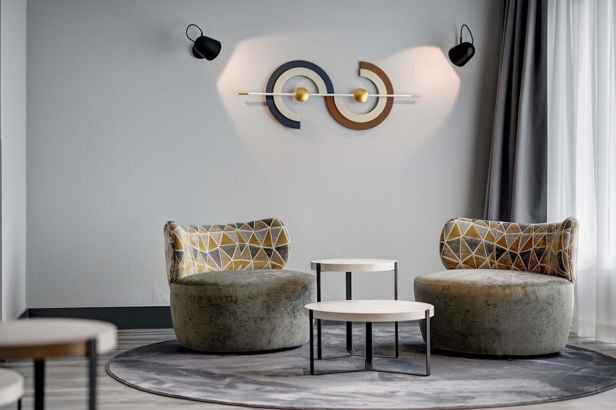 Un salon moderne avec deux canapés, une petite table ronde et un élément décoratif fixé au mur.