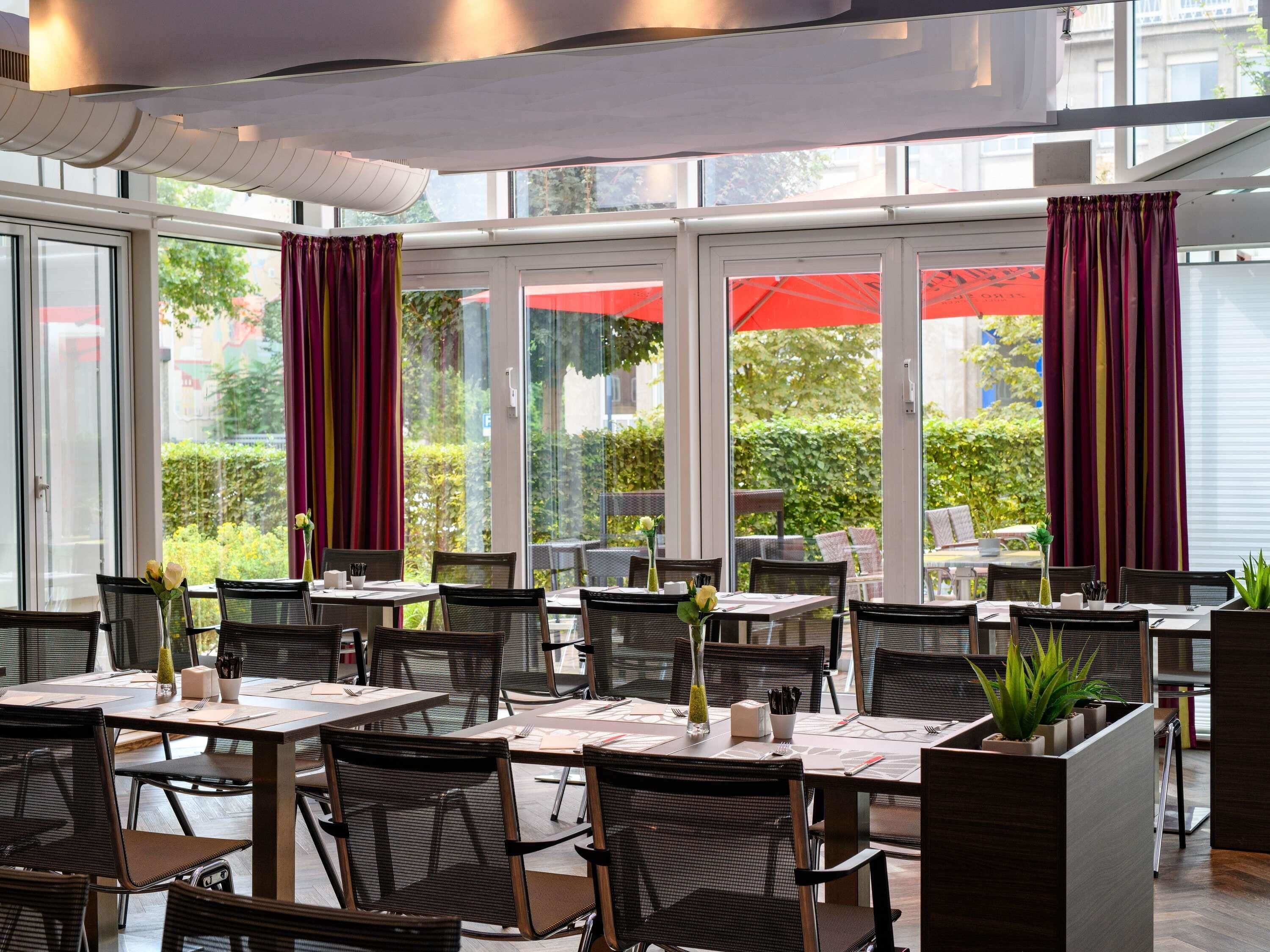 A restaurant with indoor seating, large windows, and red curtains.