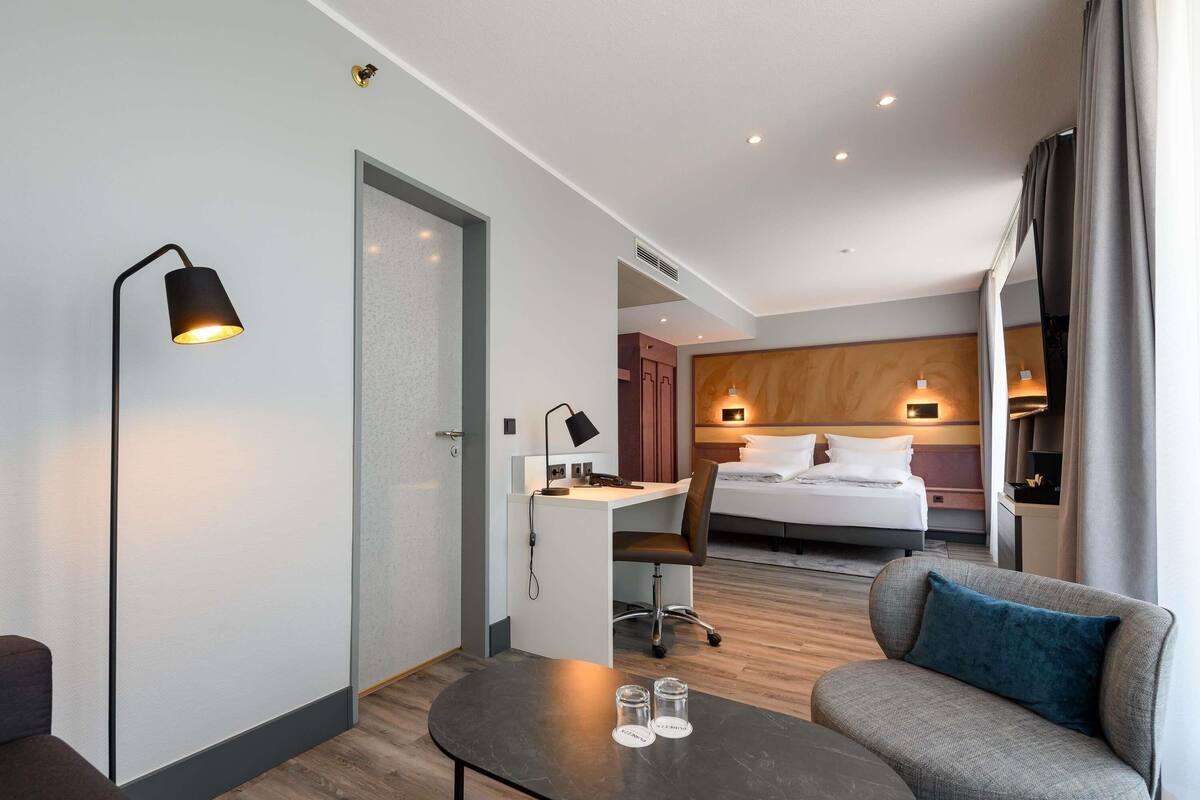 Une chambre d’hôtel moderne équipée d’un lit, d’un bureau et d’un coin salon.