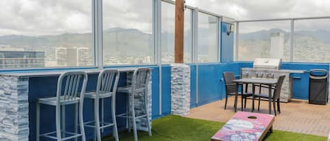 Eine Dachterrasse mit Grillplatz, Sitzgelegenheiten und Blick auf die Stadt.