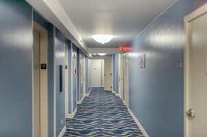 Un pasillo de hotel con alfombra estampada, puertas y señal de salida.