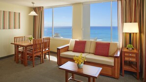 A hotel room with a dining area, a sofa with a view, and a small table with a lamp. - Pacific Monarch Hotel (Honolulu)