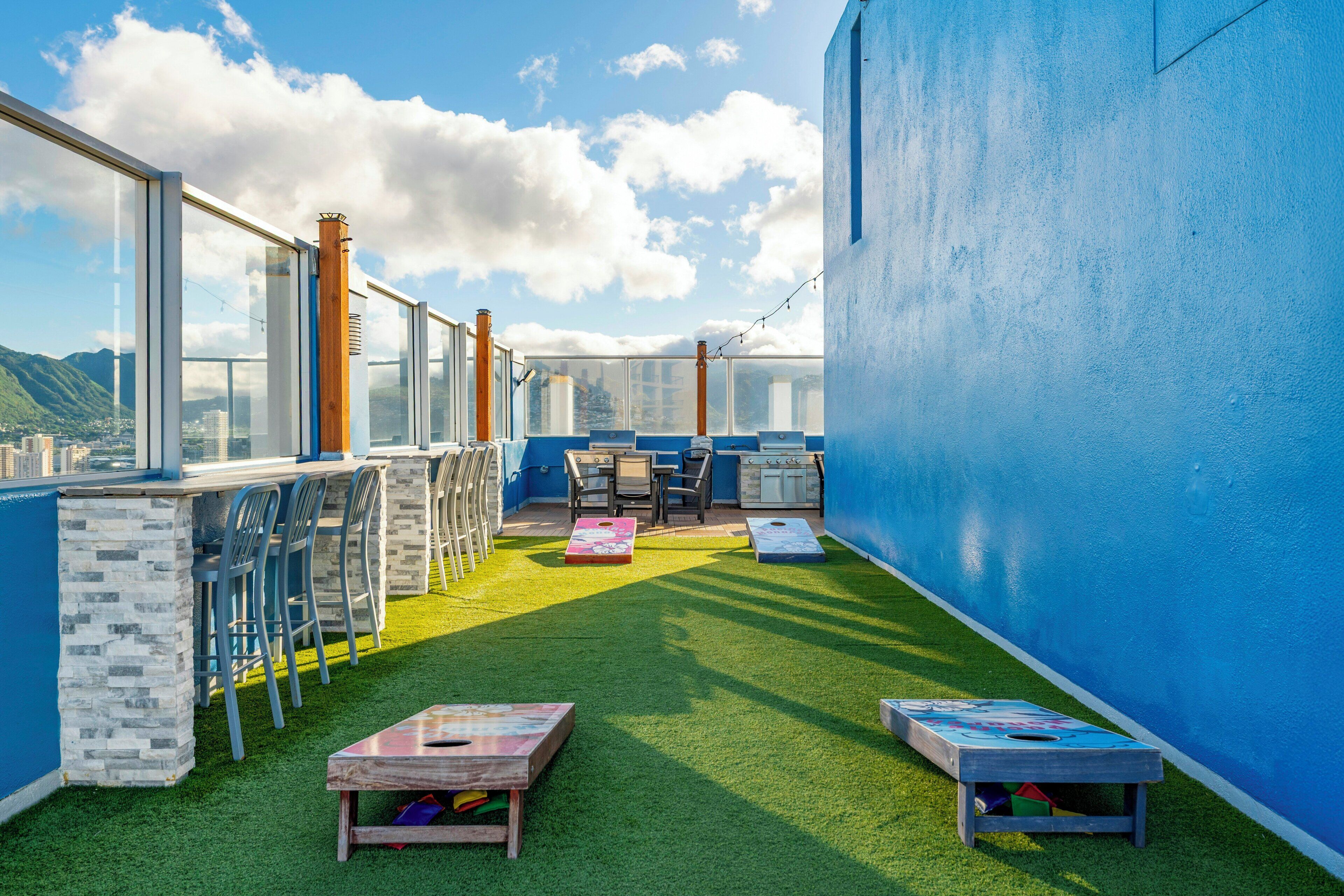 A rooftop terrace with a clear view of the city, a barbecue area, and outdoor seating.