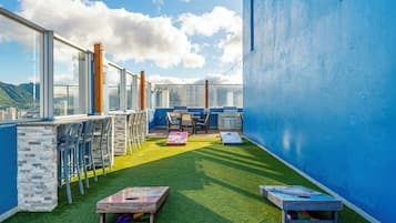A rooftop terrace with a clear view of the city, a barbecue area, and outdoor seating.