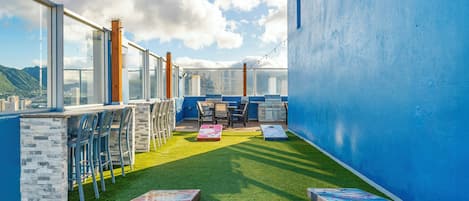 Terraza en la azotea con vistas despejadas de la ciudad, zona de barbacoa y mobiliario exterior.