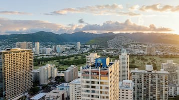 A high-rise building with multiple floors, surrounded by other high-rise buildings, and a mountainous landscape in the background.